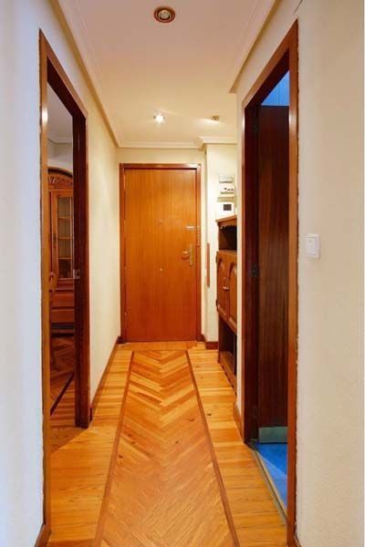 Un pasillo con suelo de madera y una puerta de madera.