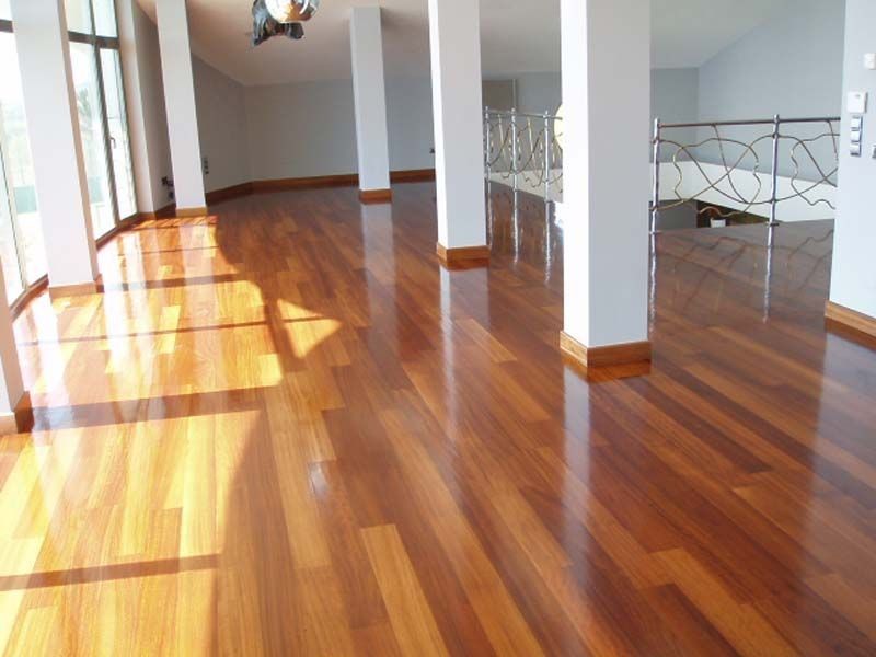 Una habitación grande con pisos de madera y columnas blancas.