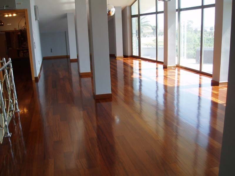 Una habitación grande con pisos de madera y muchas ventanas.