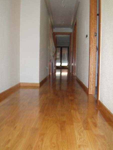 Un largo pasillo con suelos de madera y paredes blancas.