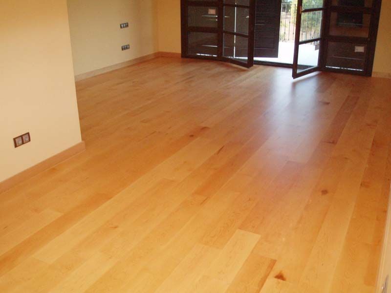 Una habitación vacía con suelo de madera y una puerta corrediza de cristal.