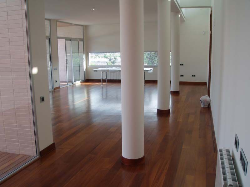 Un pasillo con suelos de madera y columnas blancas.