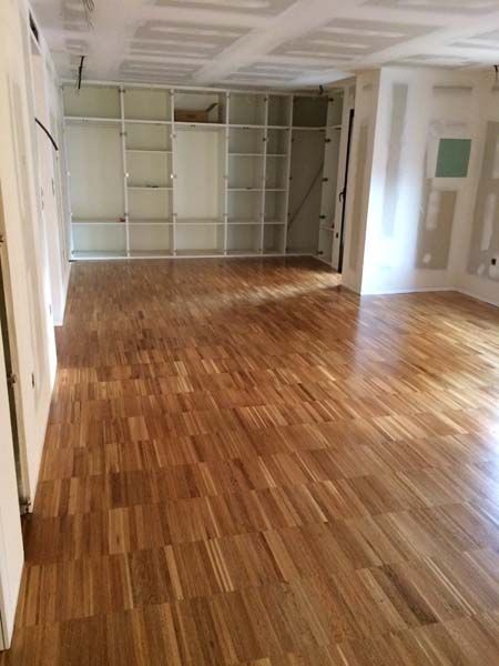 Una gran habitación vacía con suelo de madera y estantes.