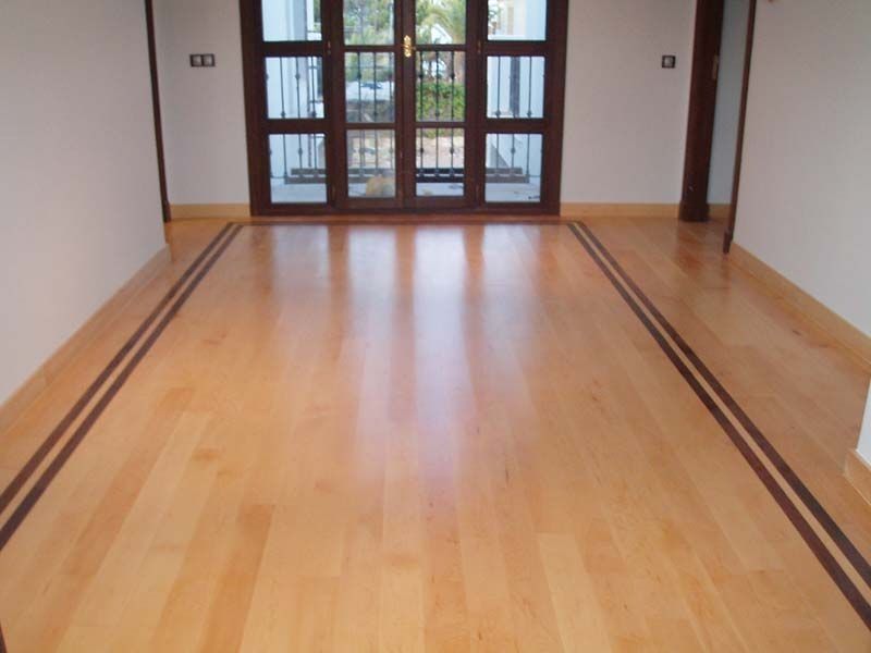 Una habitación vacía con suelo de madera y puertas corredizas de vidrio.