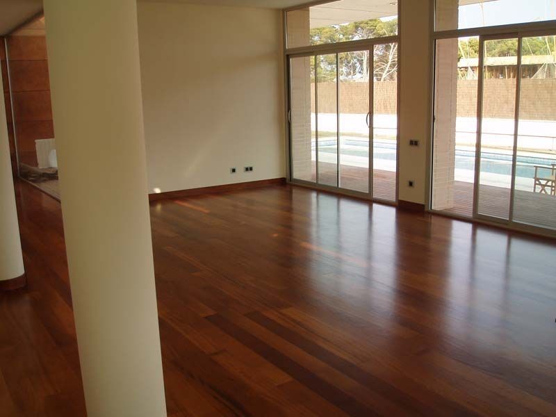 Una habitación vacía con pisos de madera y puertas corredizas de vidrio.