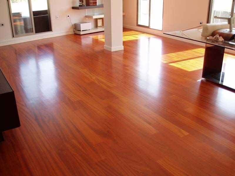 Una sala de estar con suelo de madera y una mesa de cristal.