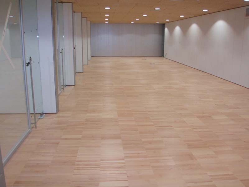 Un pasillo vacío con piso de madera y puertas de vidrio.