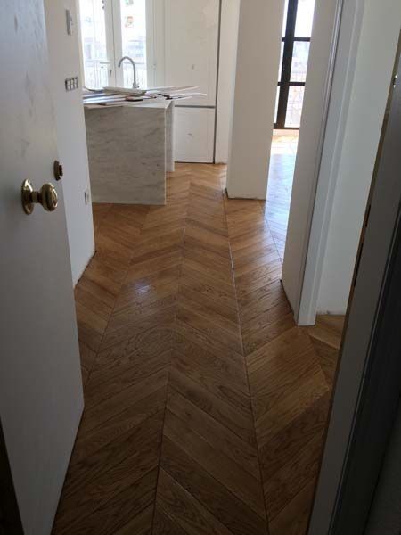 Un pasillo con suelo de madera y una puerta que conduce a una cocina.