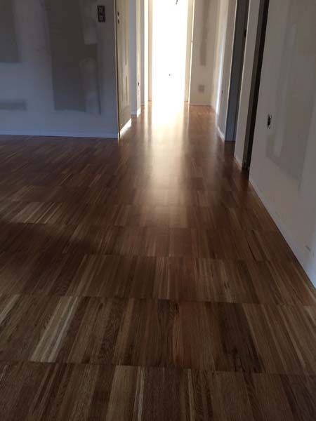 Un pasillo con suelo de madera y una luz que entra por la puerta.