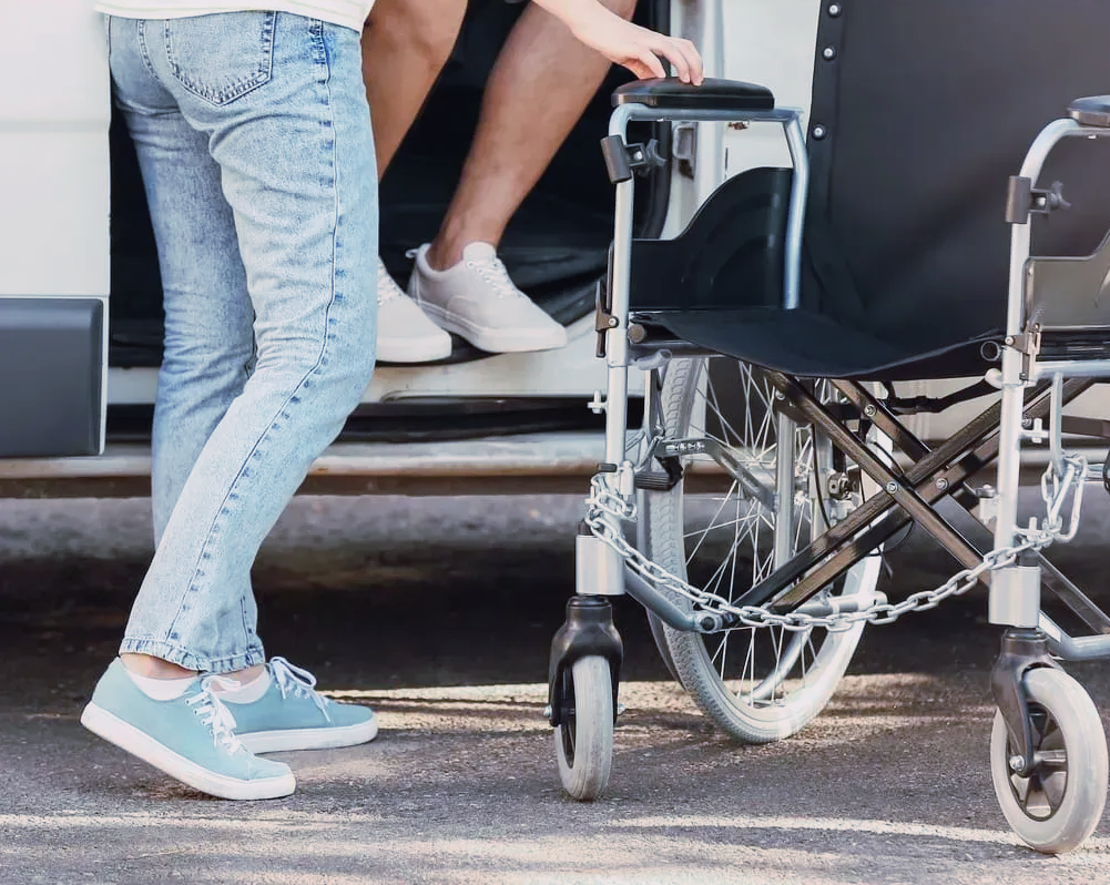 Une personne en fauteuil roulant sortant d'un véhicule de TPMR