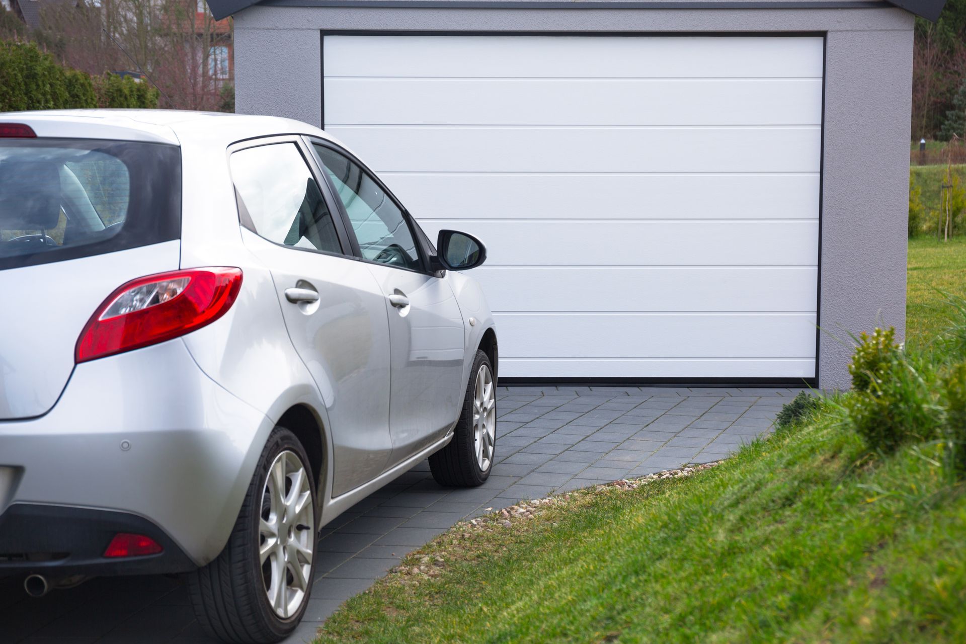 Voiture de la marque Mazda de type Mazda 2 devant une porte de garage