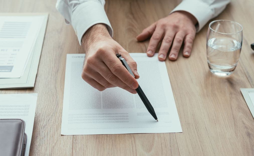 Un hombre está escribiendo en un trozo de papel con un bolígrafo.