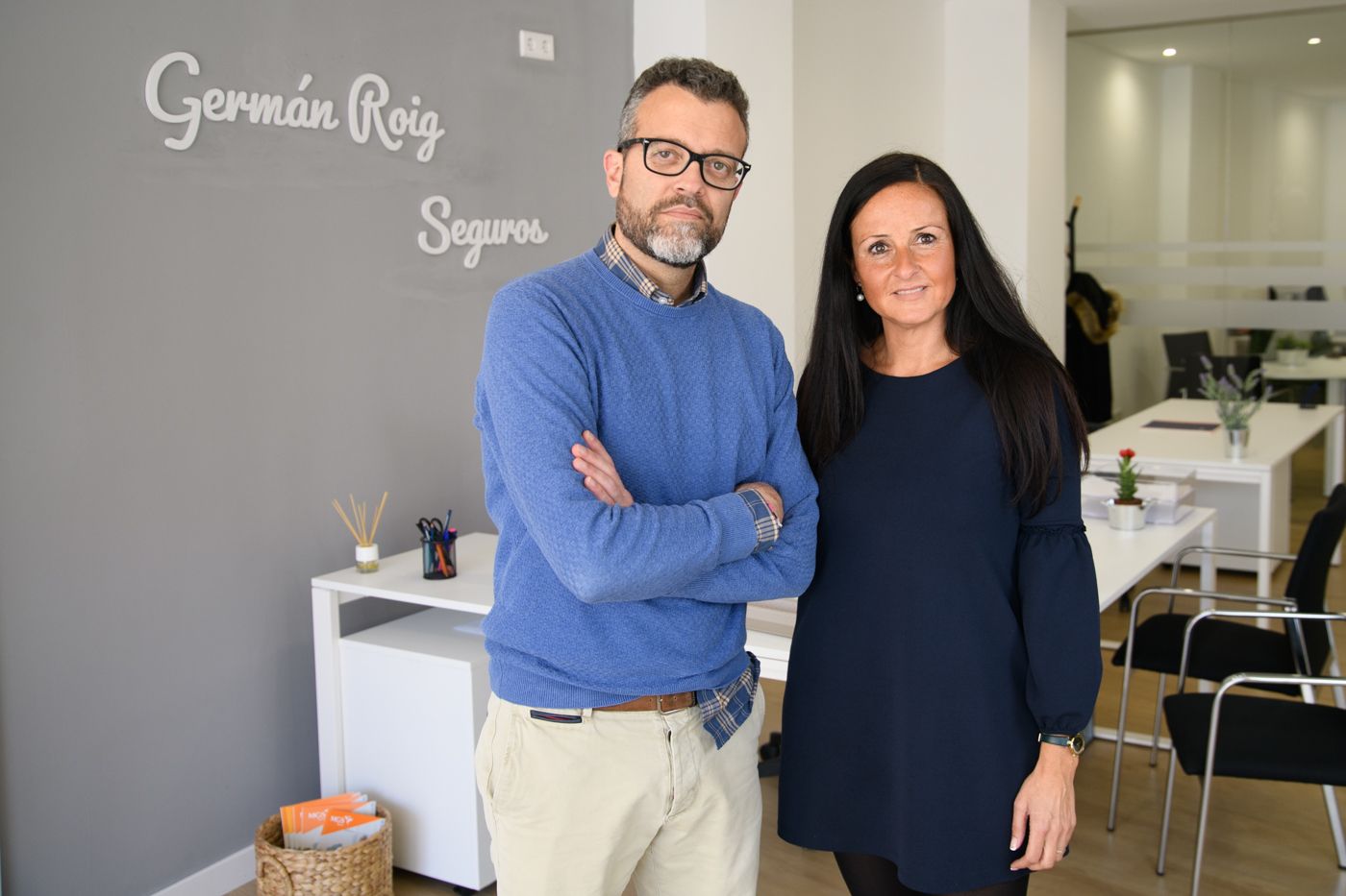 Un hombre y una mujer de pie frente a una pared que dice Germán Roig.