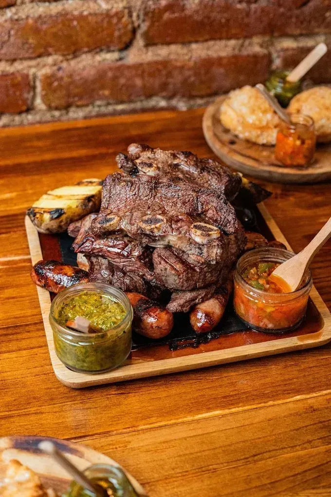 Filete a la parrilla sobre una tabla de madera con salsas, en un ambiente de restaurante rústico.