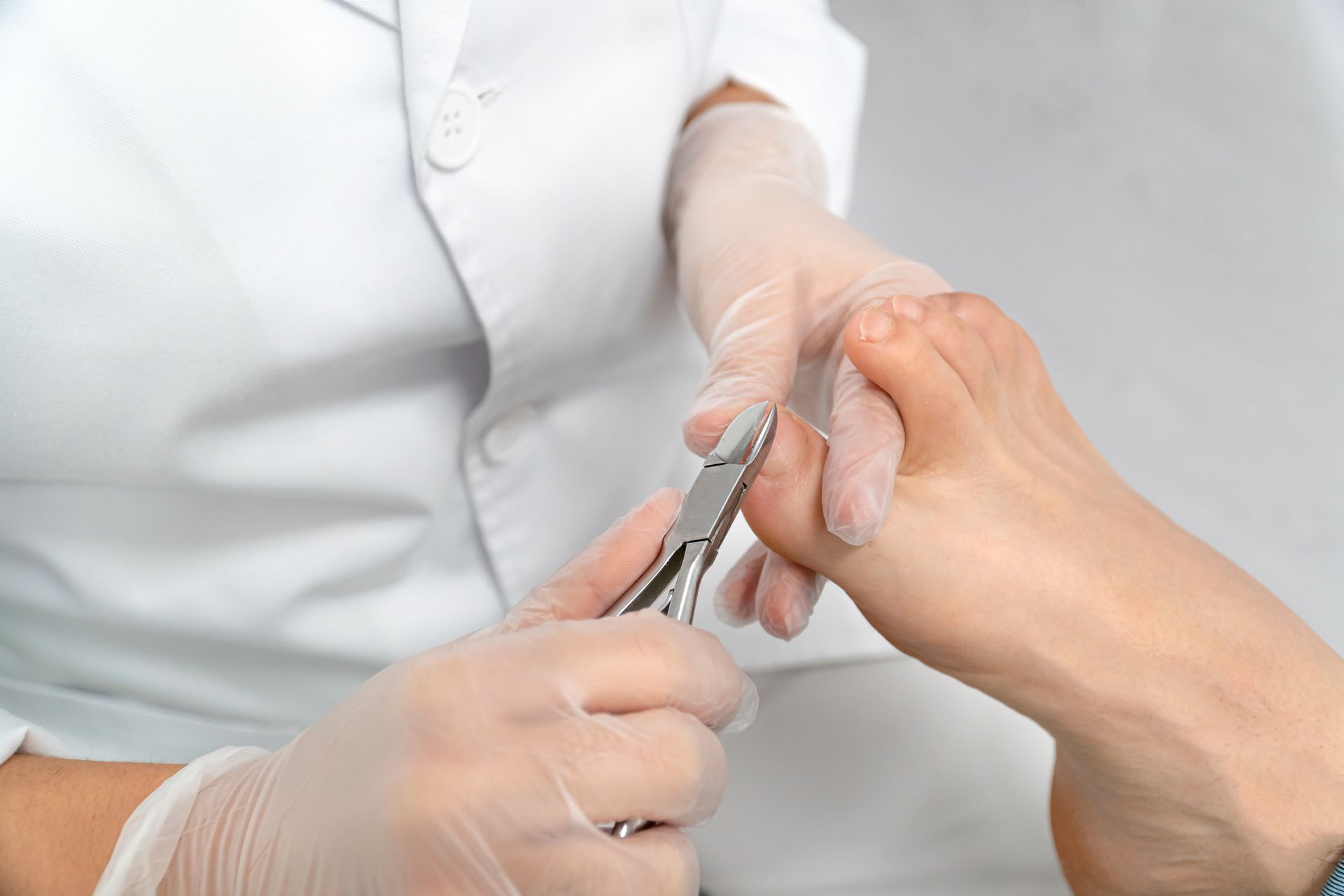 Ein Arzt schneidet einem Patienten mit einer Schere die Fußnägel.