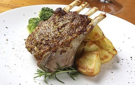 Un plato blanco cubierto con un trozo de carne y patatas.