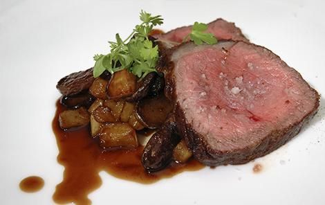 Un plato blanco cubierto con un trozo de carne y salsa.