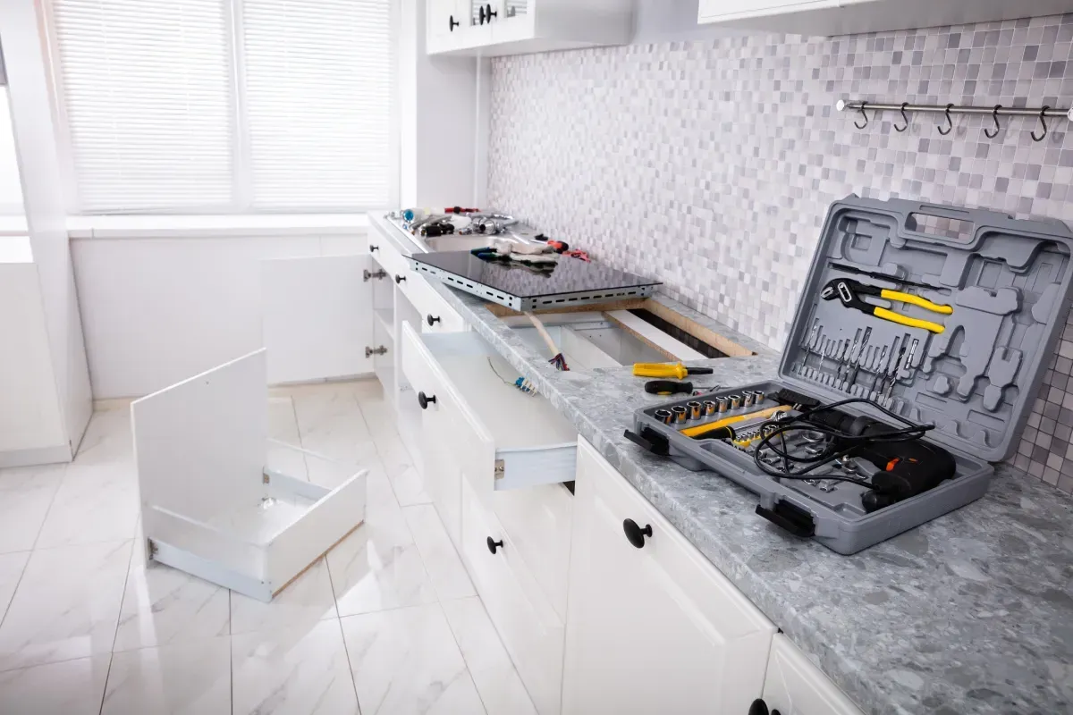 Mueble de cocina en reparación, con cajón abierto y caja de herramientas sobre la encimera.