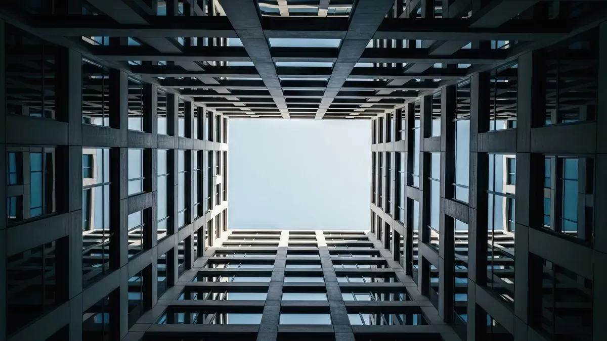 Mirando hacia arriba a través del centro abierto de un edificio moderno de varios pisos hacia el cielo azul.
