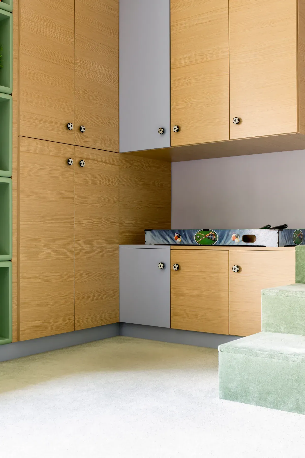 Gabinetes de cocina: madera clara y gris, estantes verdes, piso y escalones de baldosas verde claro y gris.