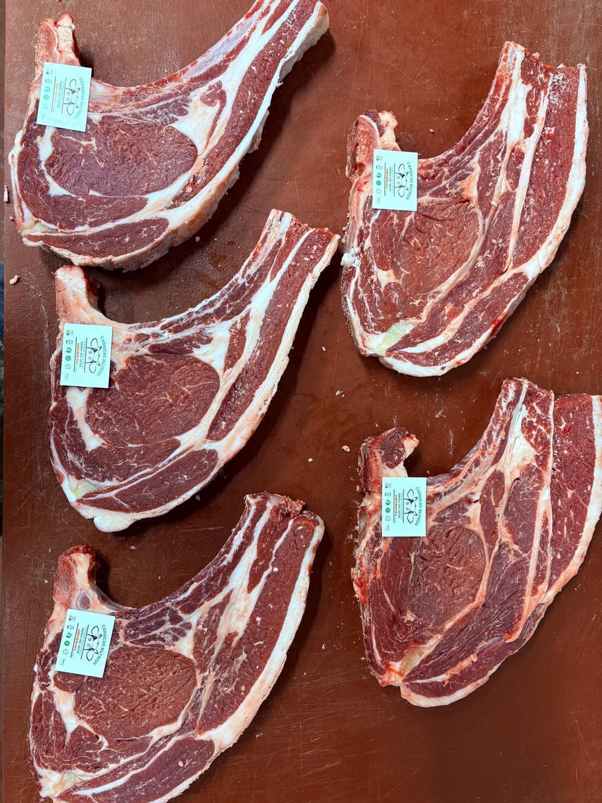 Filetes de ternera cruda con etiquetas dispuestos sobre una superficie de madera.