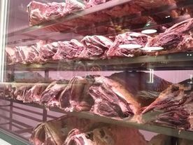 Cortes de carne cruda en exhibición en una vitrina refrigerada, que muestra varias porciones de carne y con hueso.