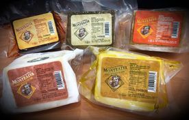 Cinco bloques de queso en envase al vacío, de varios colores, con un logotipo que representa la cara de un hombre.