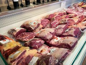 Vitrina llena de diversos cortes de carne roja cruda en una carnicería, bien iluminada y lista para su compra.