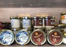 Tarros de productos alimenticios gourmet en un estante, con marcas como Andazul y Montralzer, con varios diseños y colores de etiquetas.