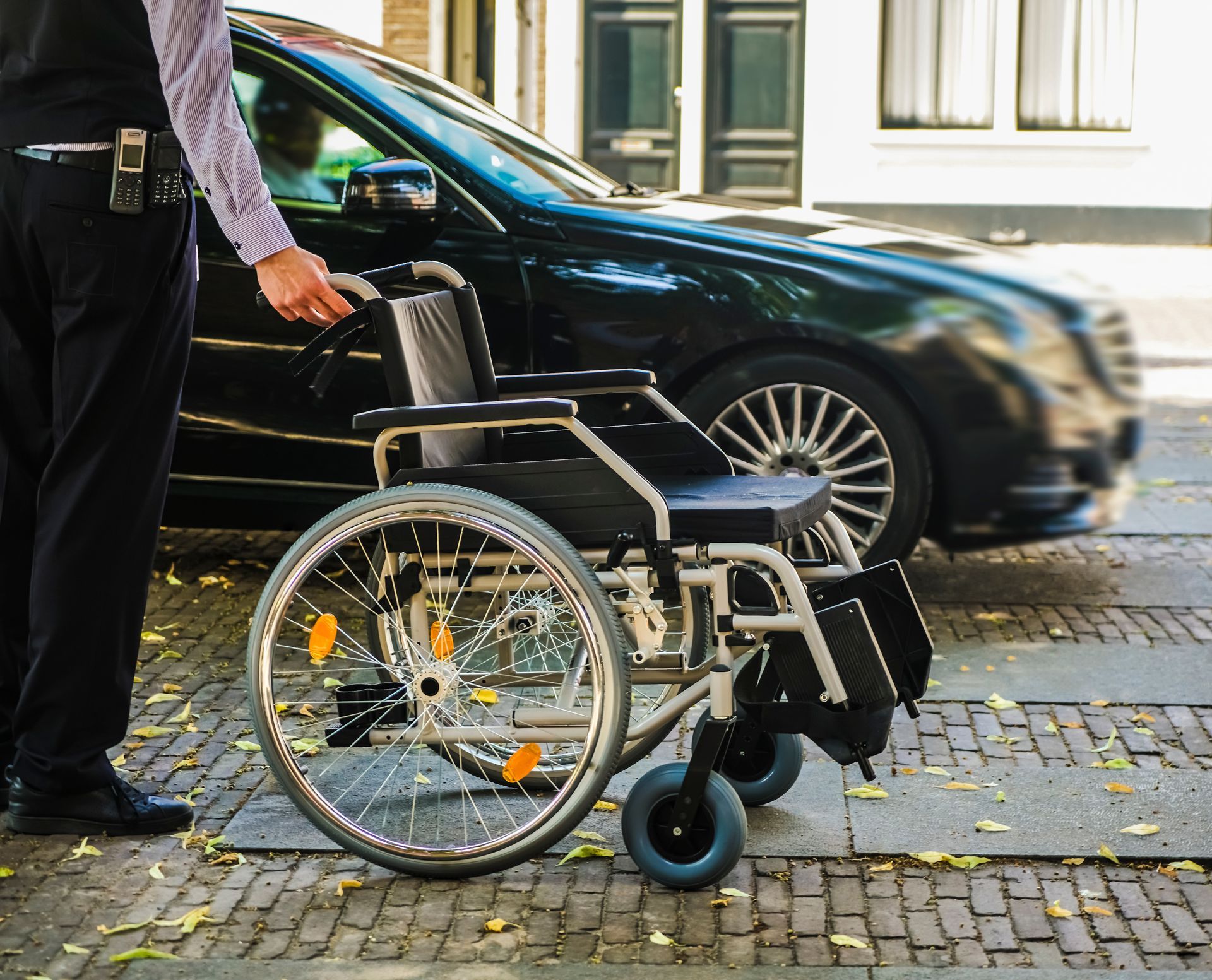 Un homme tient un fauteuil roulant devant une voiture