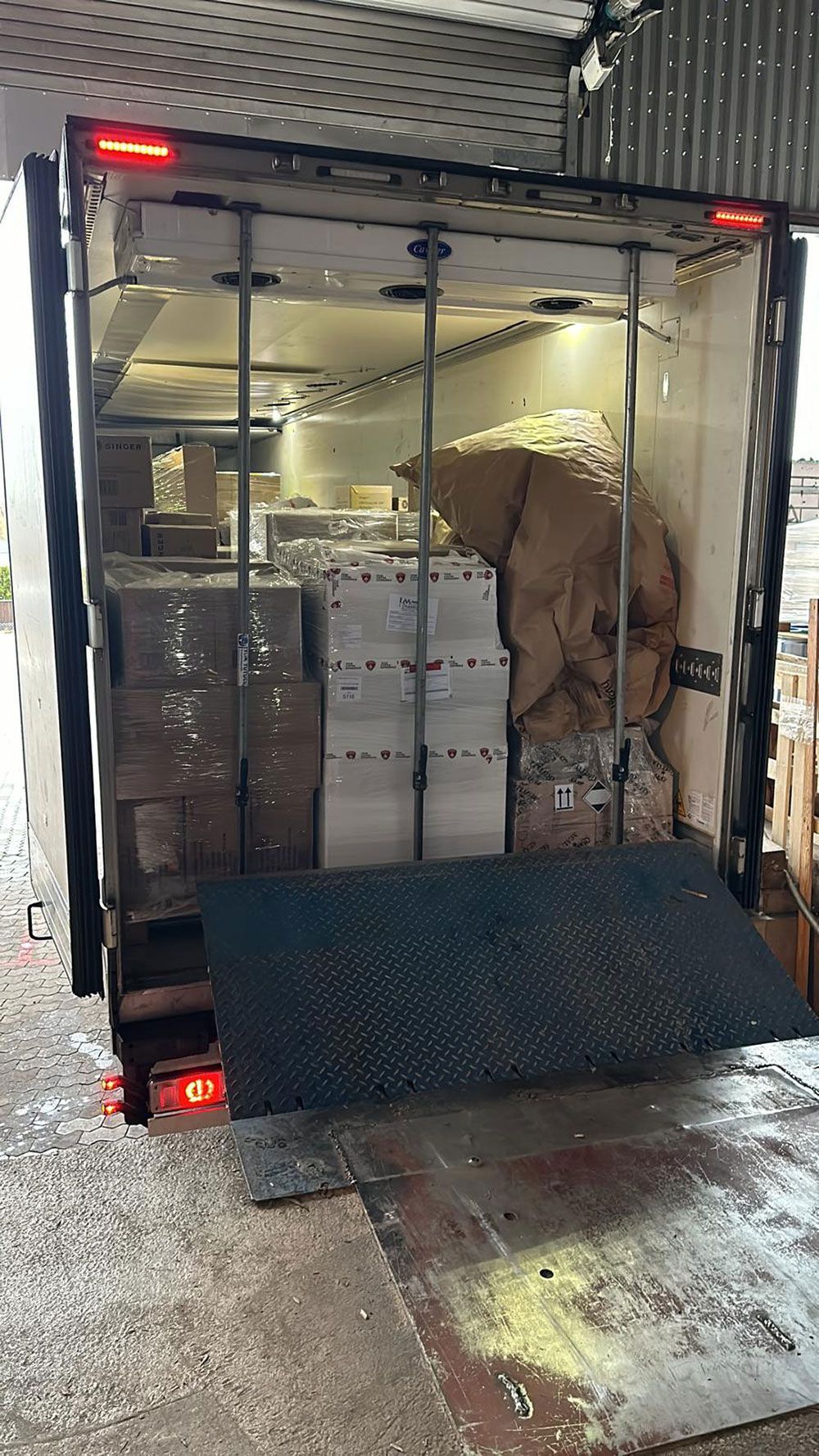 Die Ladefläche eines Lastwagens voller Kisten und einer Rampe.