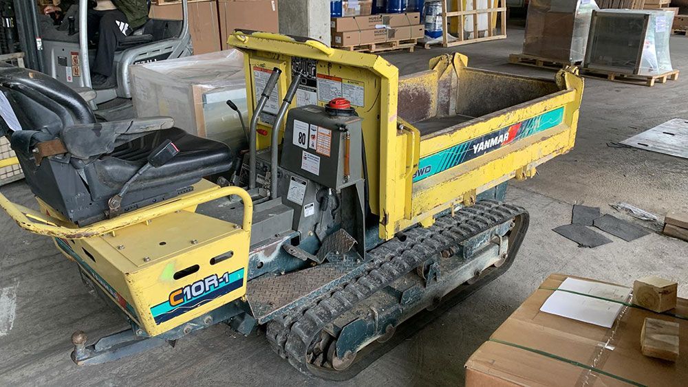 Ein kleiner gelber Muldenkipper steht in einer Lagerhalle.