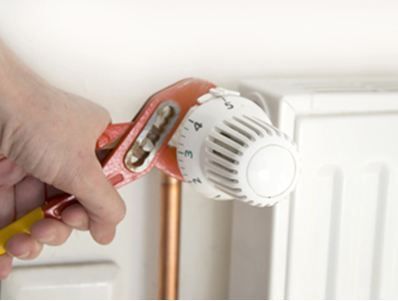 Una persona está arreglando un radiador con una llave inglesa.