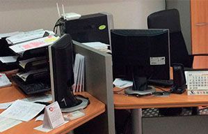 Dos monitores de computadora están sobre un escritorio de madera en un cubículo de oficina.