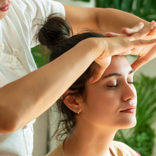 Una mujer está recibiendo un masaje de cabeza en un spa.