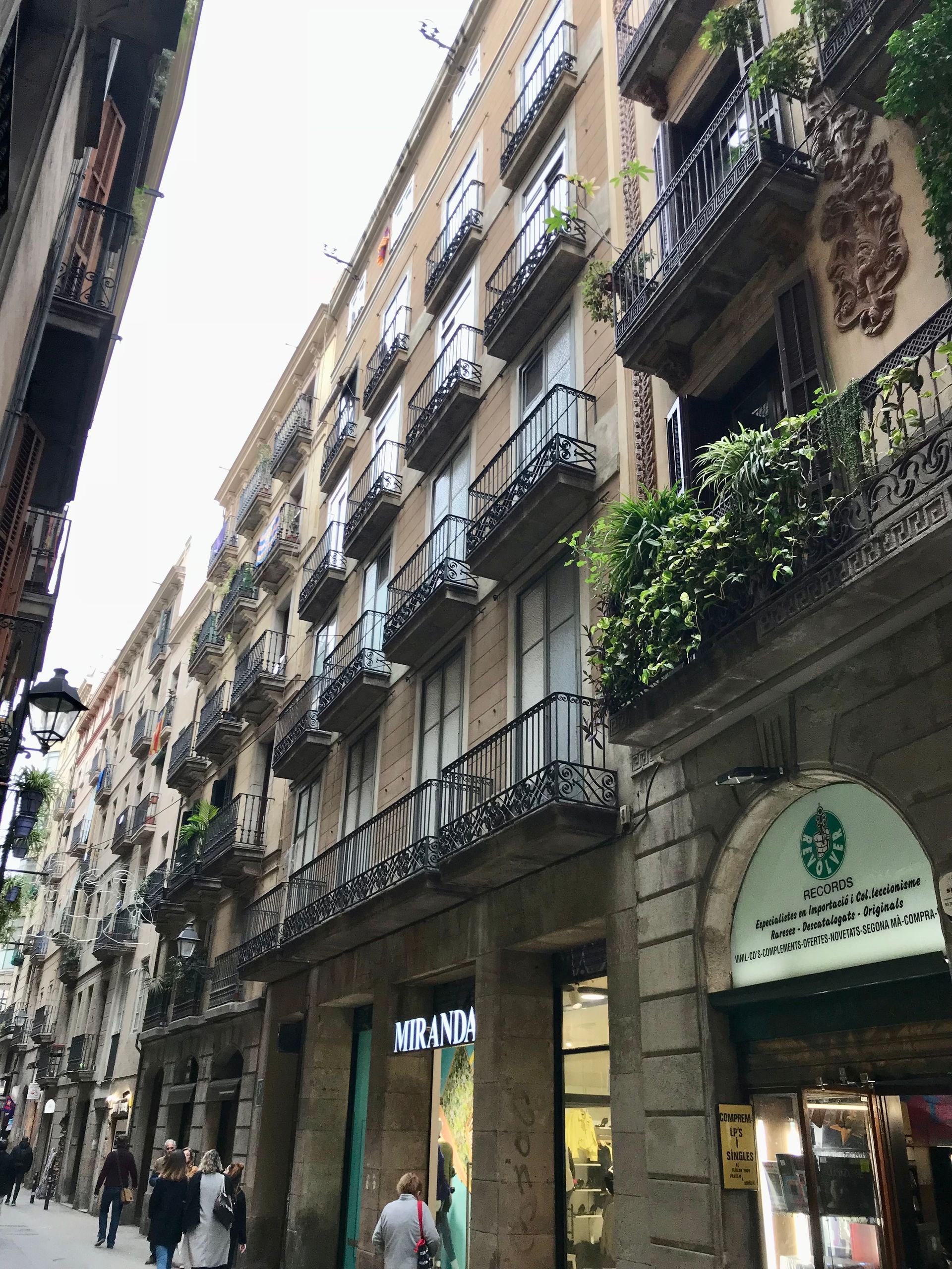 Un grupo de personas camina por una calle estrecha frente a un gran edificio.