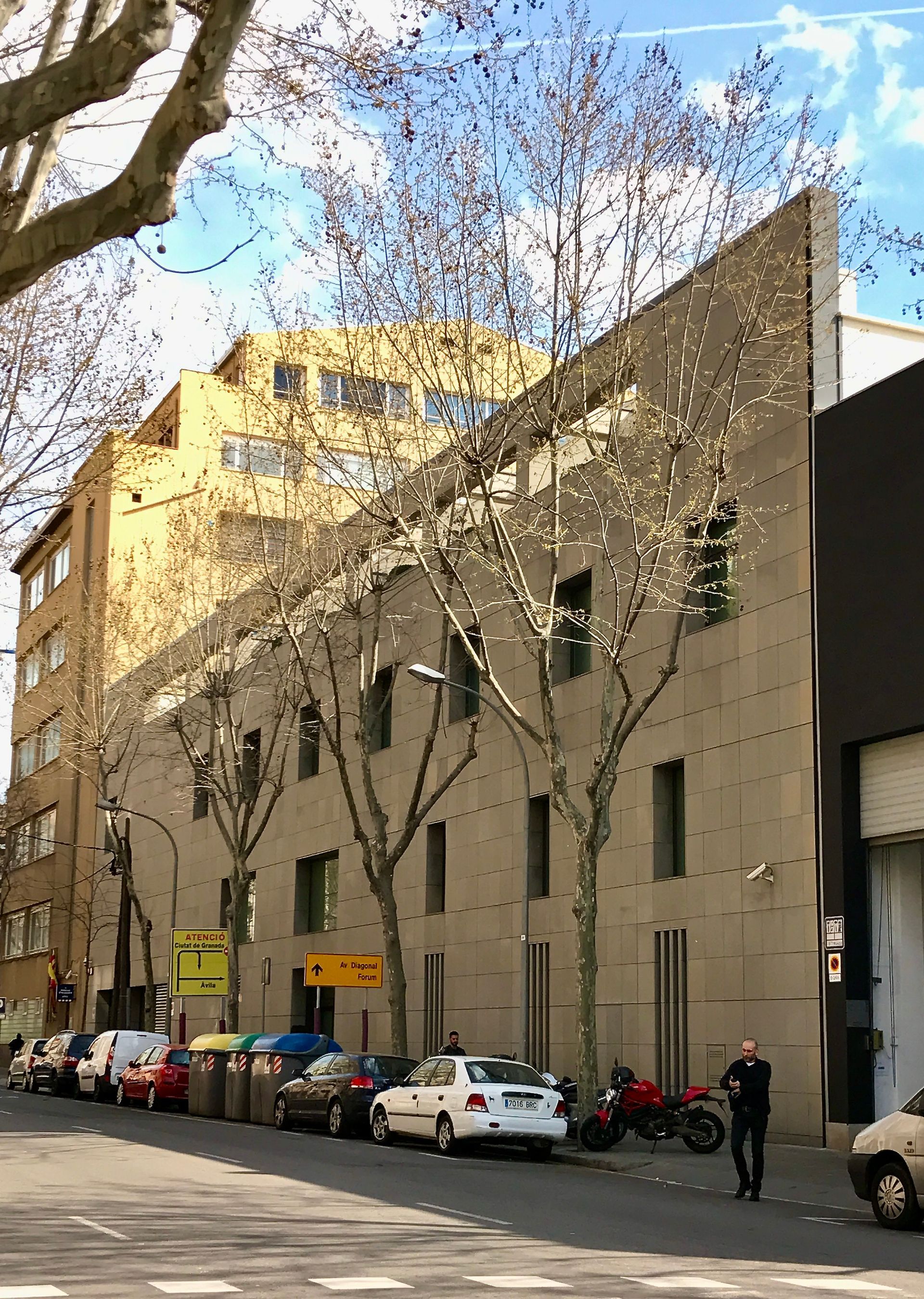 Un edificio con muchos coches aparcados delante.