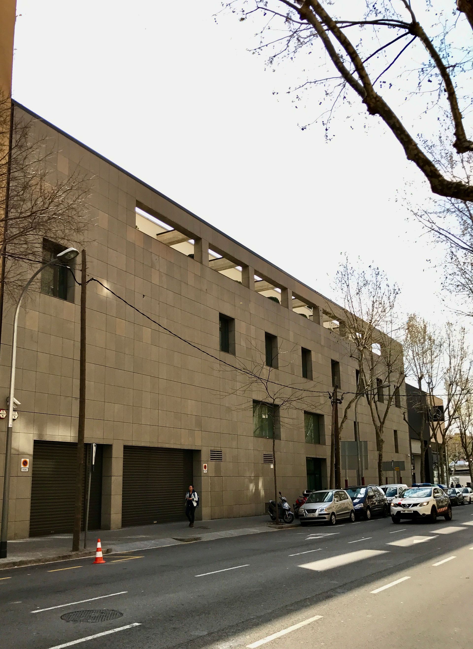 Un gran edificio con muchos coches aparcados delante.