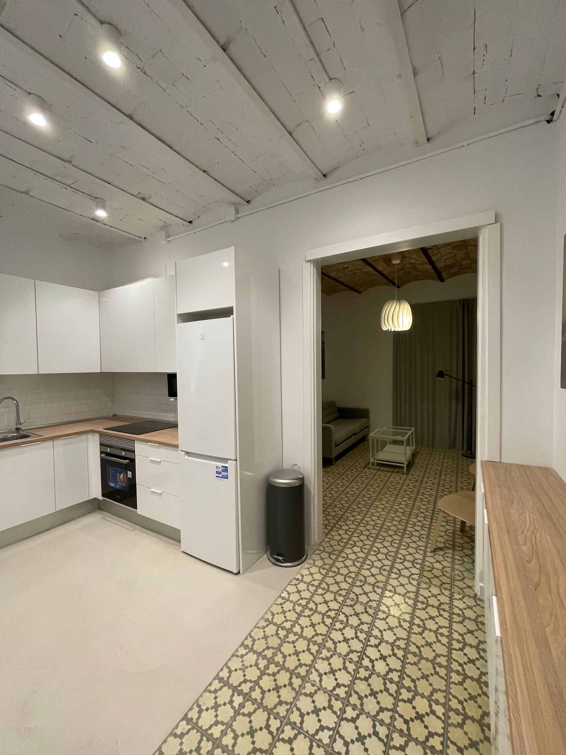 Una cocina con gabinetes blancos, un refrigerador, un fregadero y una estufa.