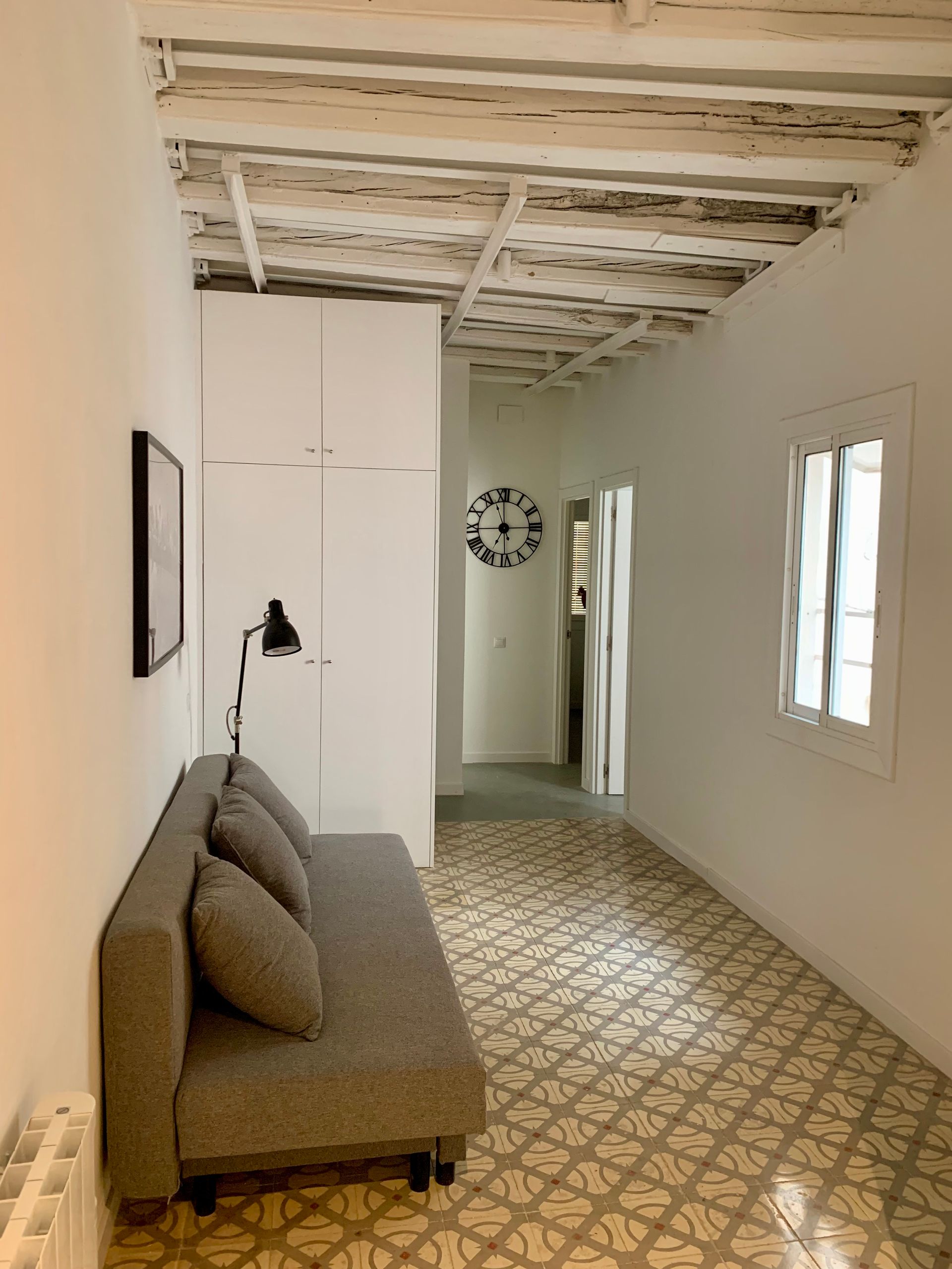 Una sala de estar con un sofá y un reloj en la pared.