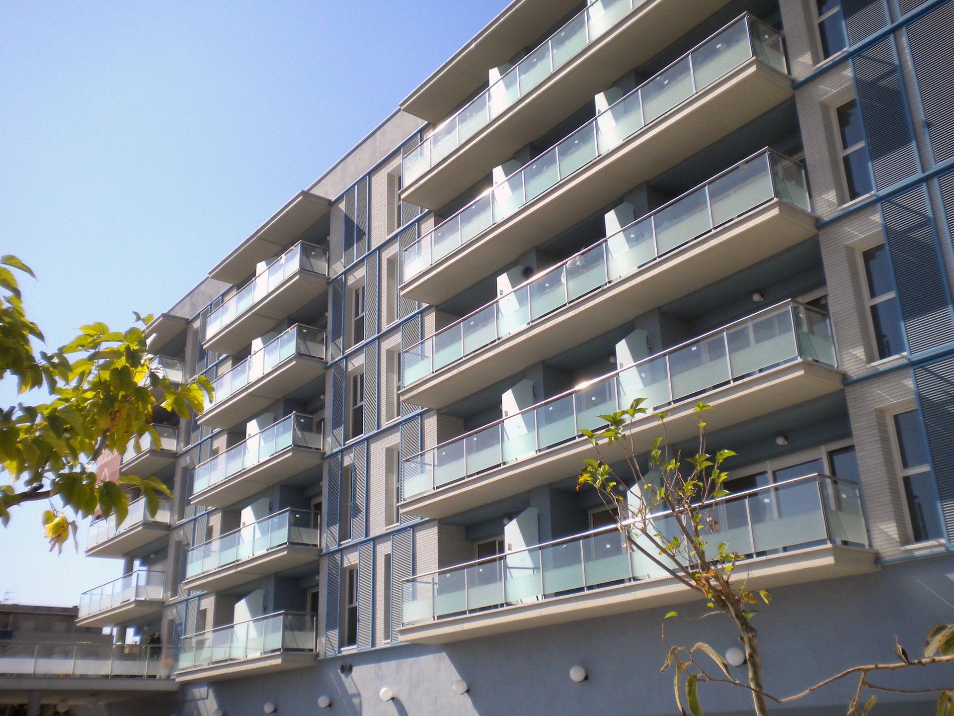 Un gran edificio de apartamentos con muchos balcones en un día soleado.