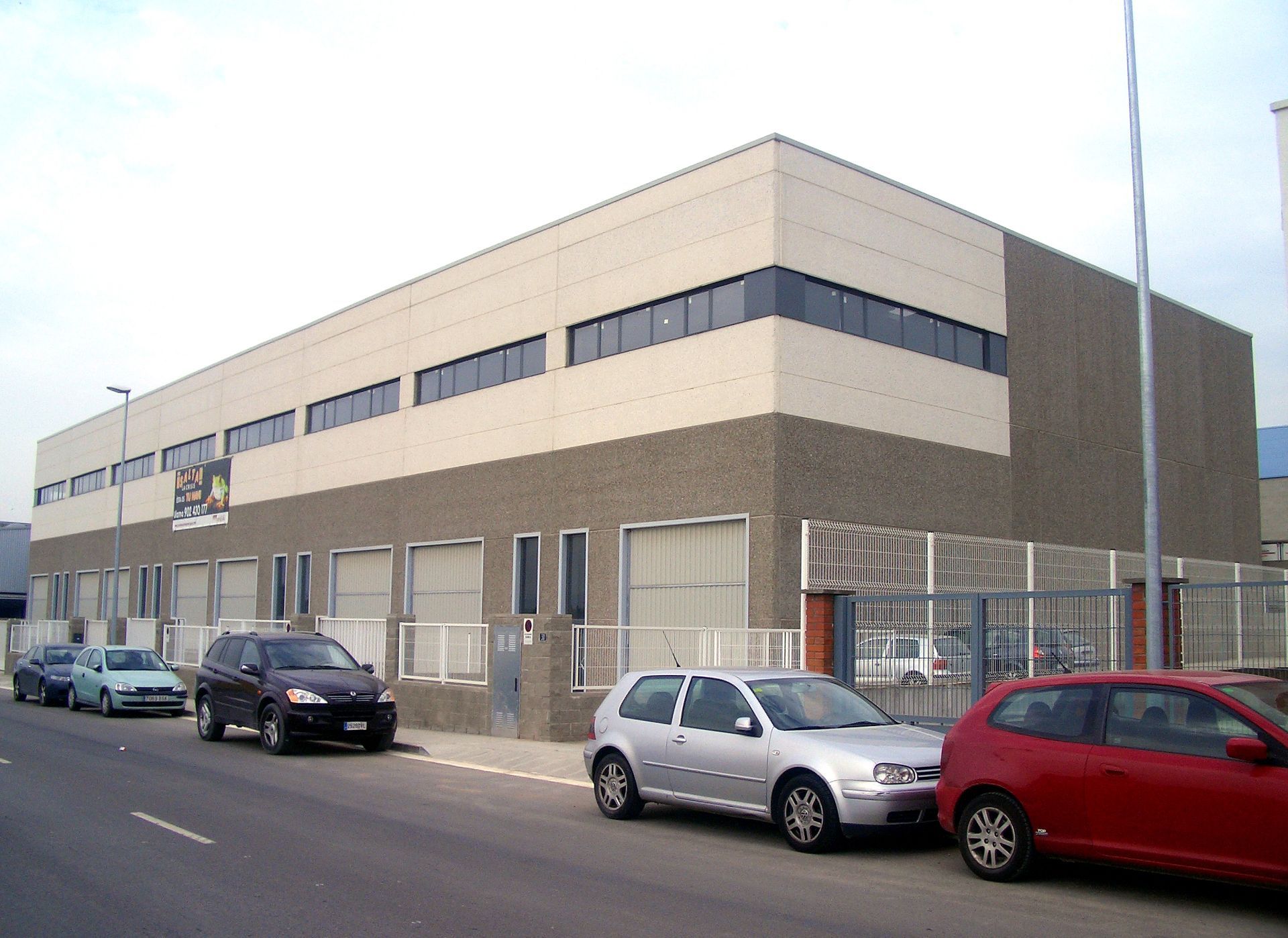 Varios coches están aparcados delante de un gran edificio.