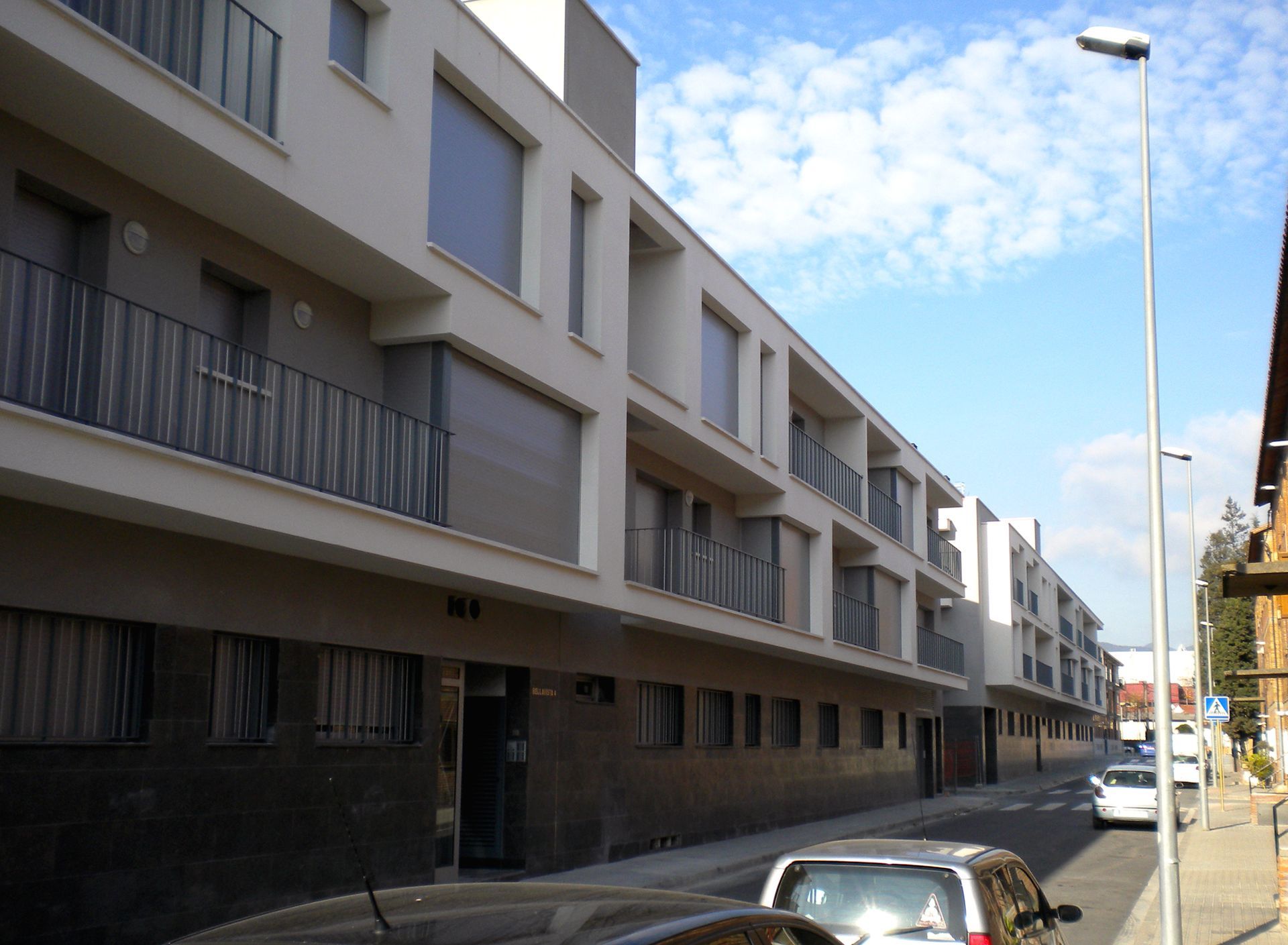 Un coche está aparcado delante de un edificio con balcones.