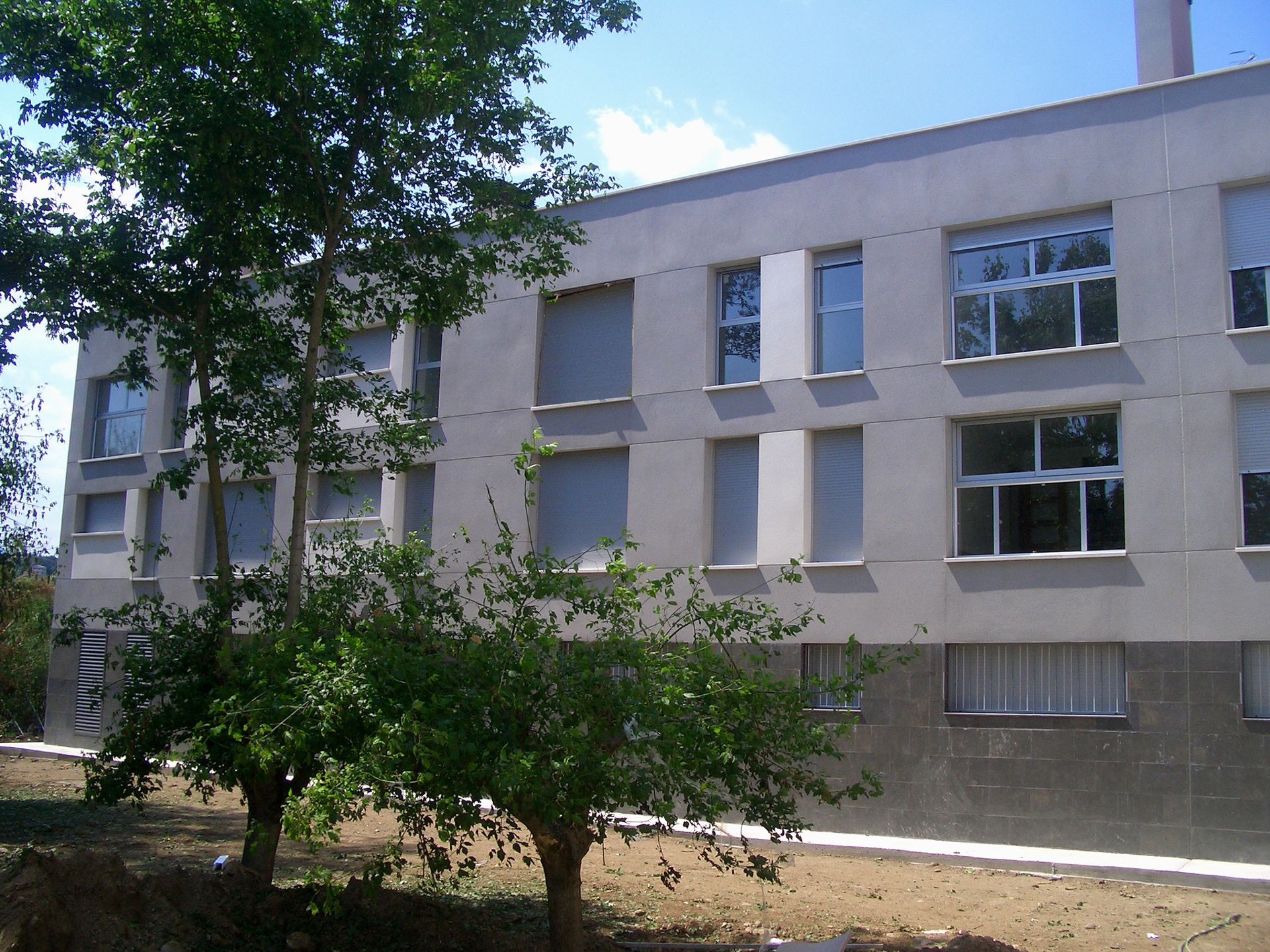 Un edificio con muchas ventanas y árboles delante.
