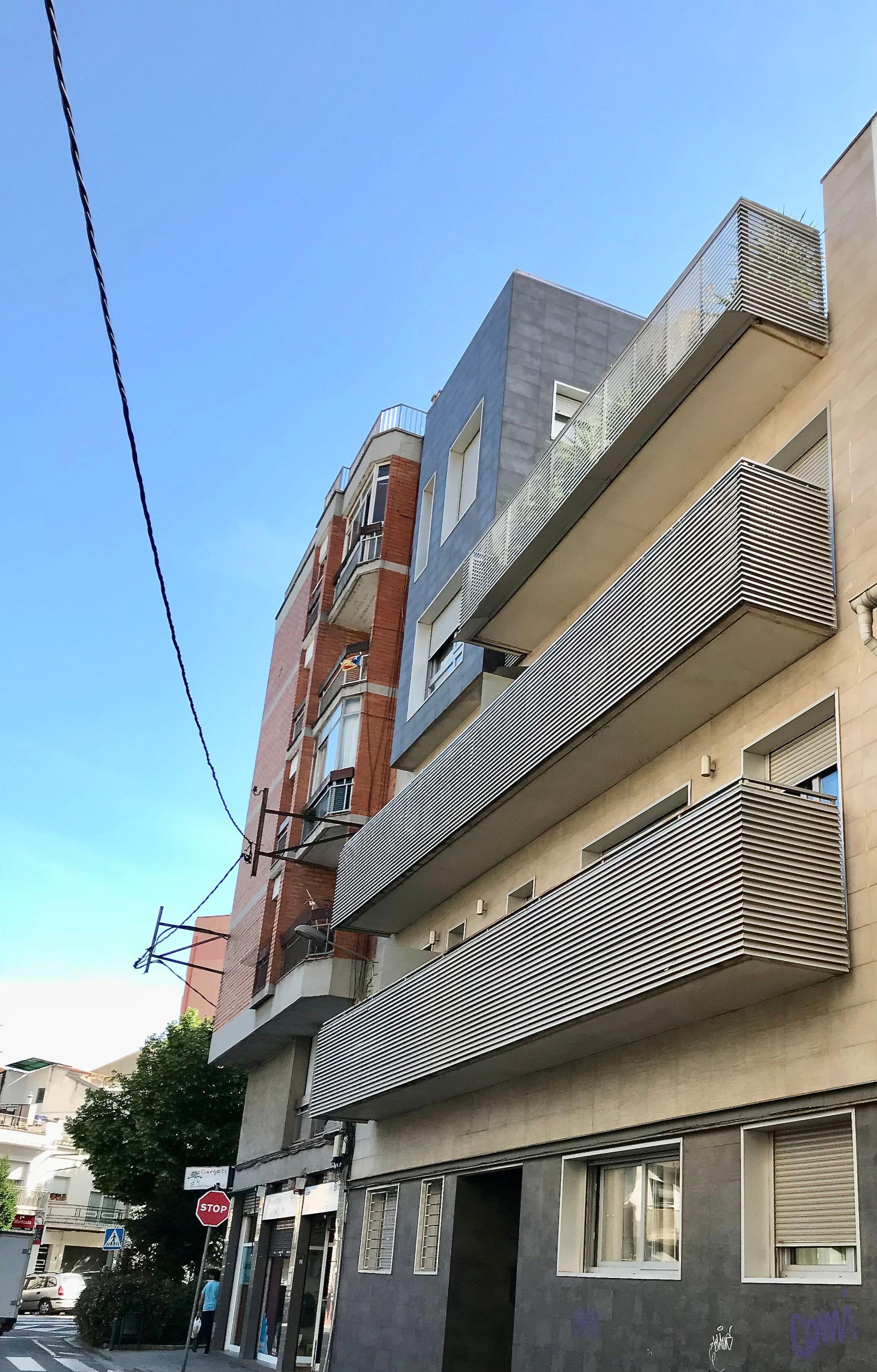 Un edificio con balcones y un cielo azul al fondo.