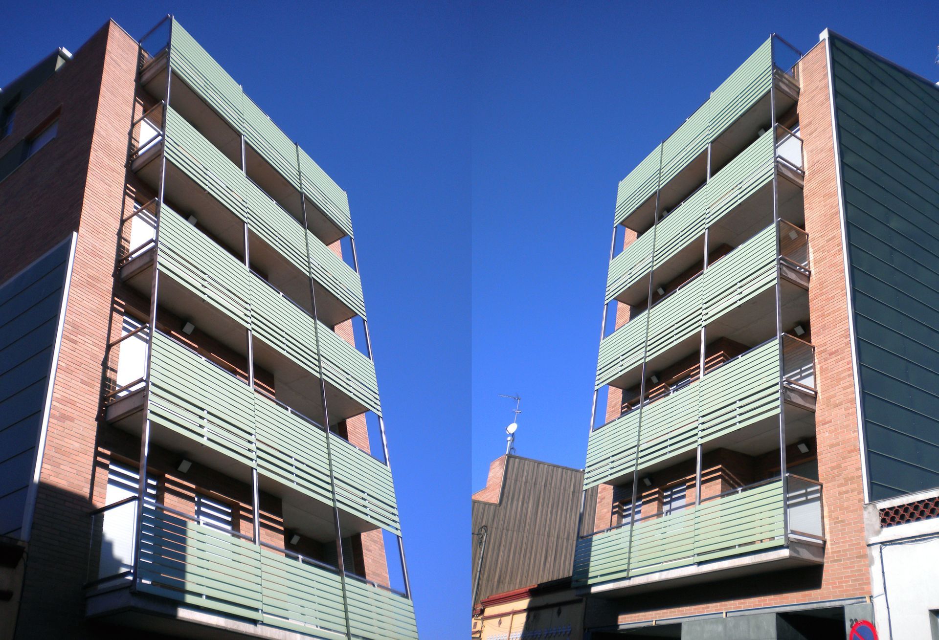 Un edificio de ladrillo con balcones verdes y un cielo azul al fondo.