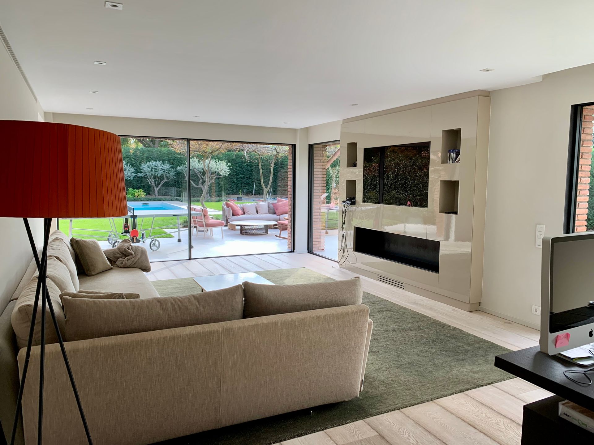 Una sala de estar con sofá, televisión, lámpara y puertas corredizas de vidrio que conducen a un patio.