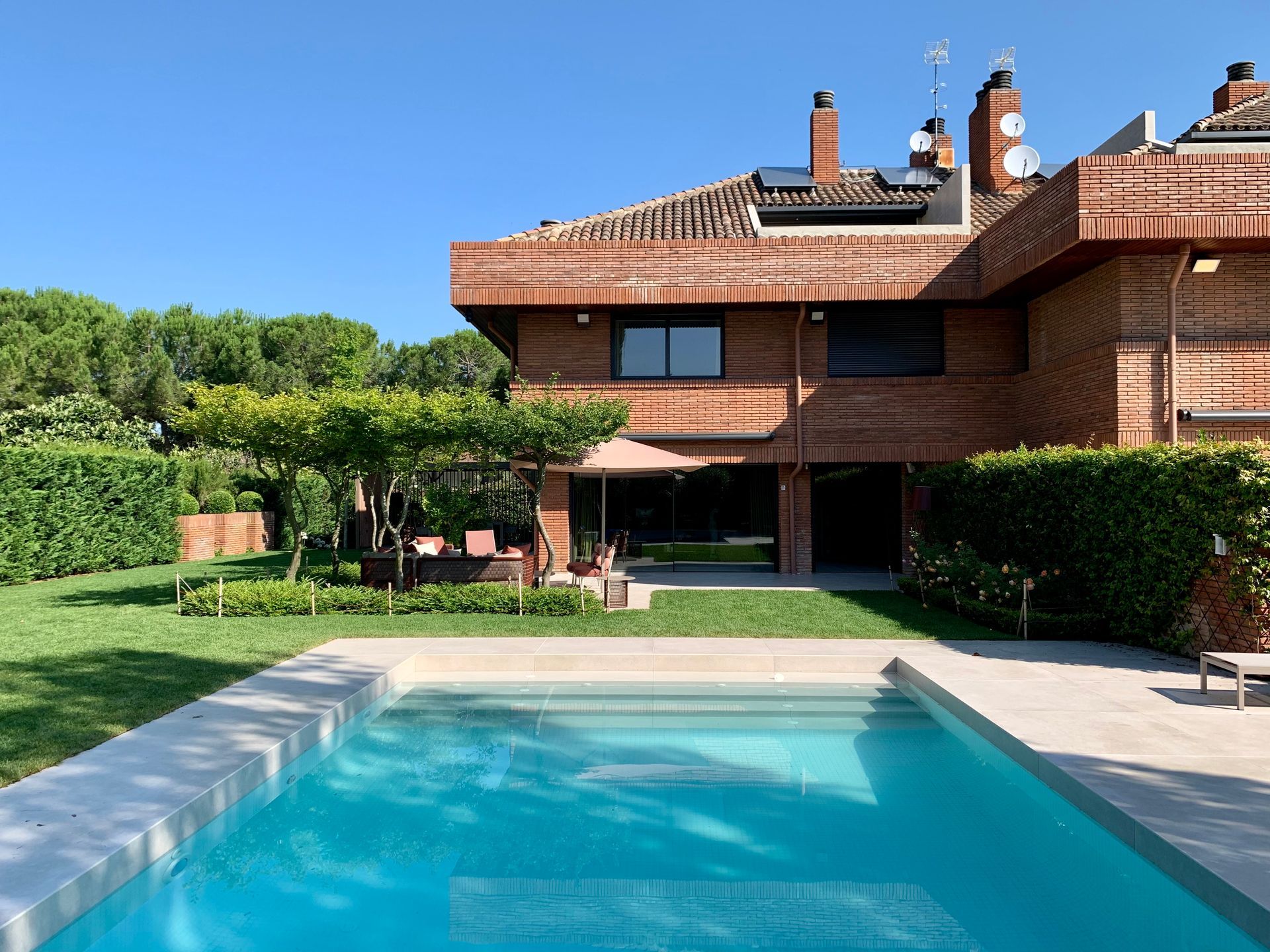 Una gran casa de ladrillo con una piscina delante de ella.