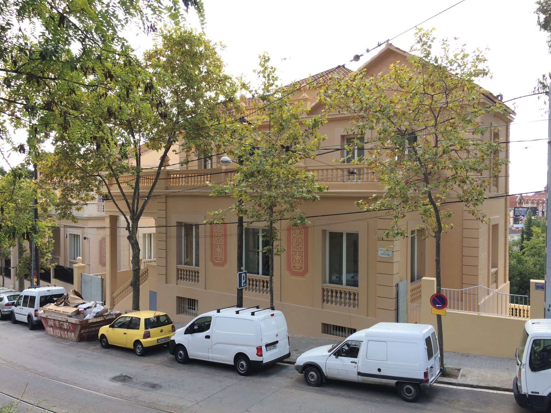Un gran edificio con muchos coches aparcados delante.