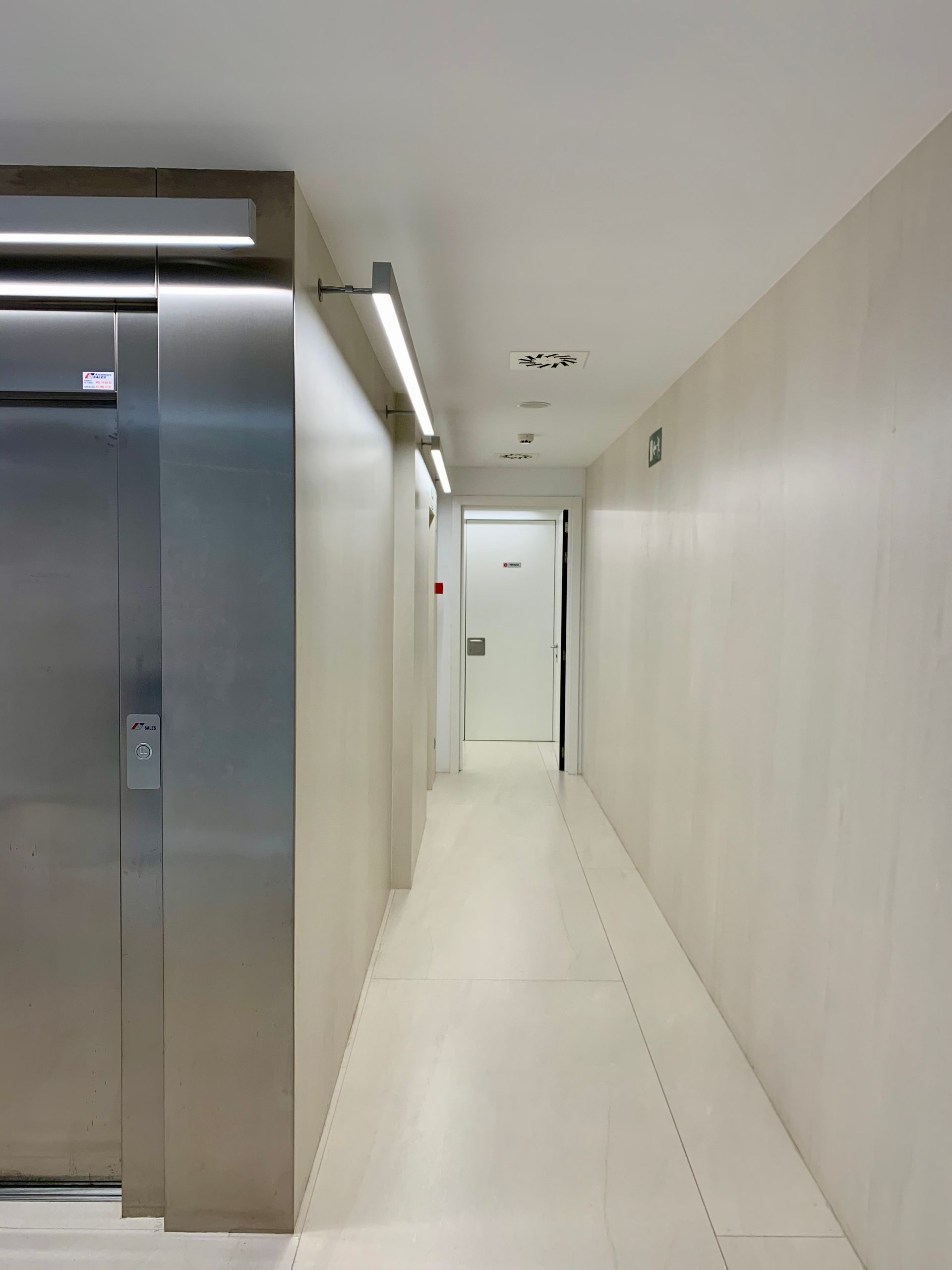 Un largo pasillo con una puerta de acero inoxidable.